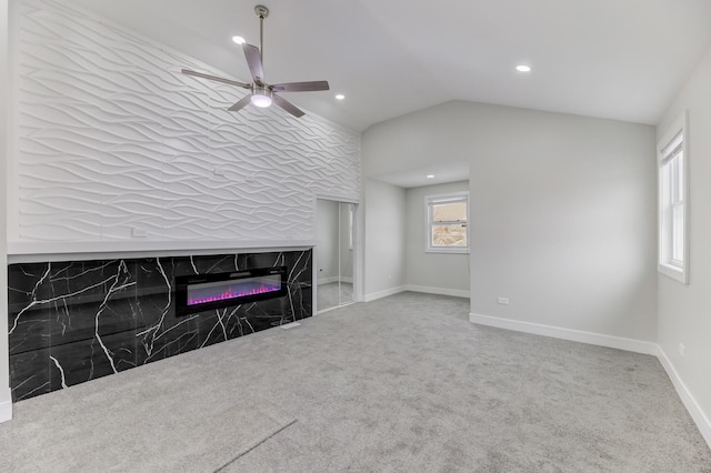 unfurnished living room with lofted ceiling, recessed lighting, a high end fireplace, baseboards, and carpet