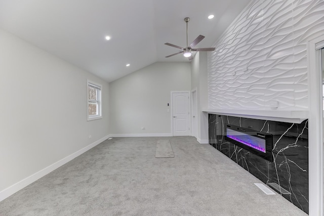 unfurnished living room featuring lofted ceiling, ceiling fan, carpet floors, baseboards, and a glass covered fireplace