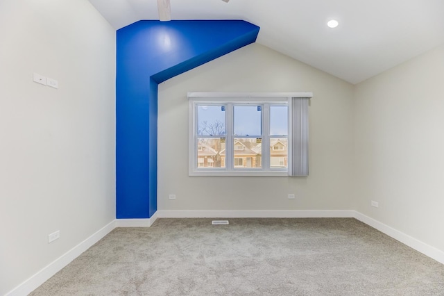 empty room with light colored carpet, vaulted ceiling, and baseboards