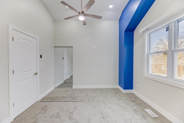 empty room with a ceiling fan, visible vents, light carpet, and baseboards