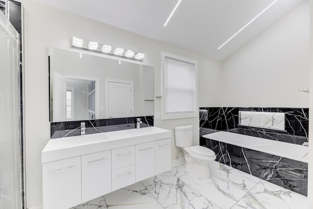 bathroom featuring toilet, marble finish floor, a tub with marble appearance, and a sink