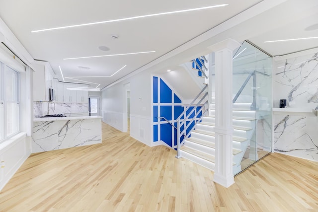 interior space featuring stairs, a wainscoted wall, and light wood-style floors