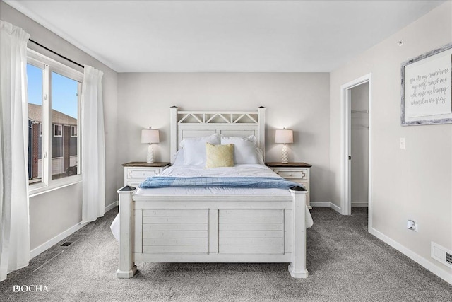 bedroom featuring visible vents, carpet flooring, a walk in closet, and baseboards