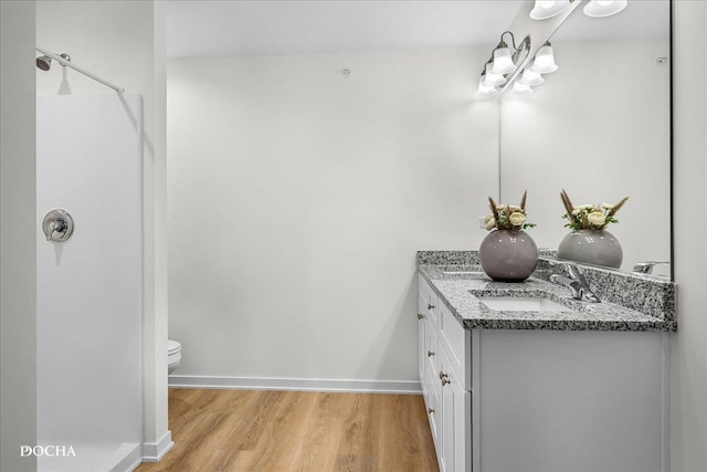 bathroom with toilet, wood finished floors, vanity, and baseboards