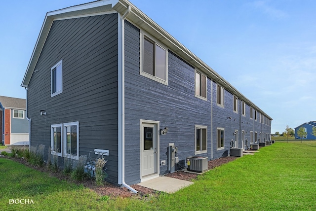 rear view of property with central AC and a yard