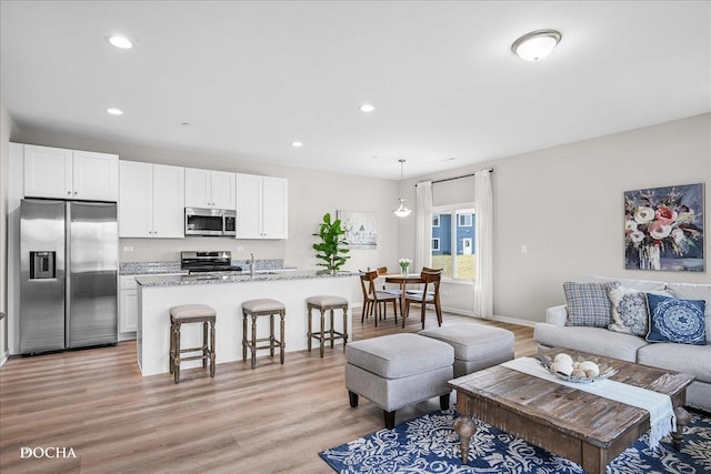 living room with baseboards, light wood finished floors, and recessed lighting