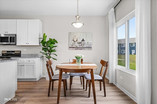 dining area with light wood-type flooring and baseboards