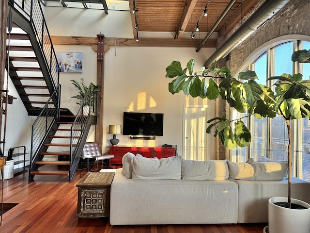 living room with rail lighting, stairs, dark wood finished floors, and beamed ceiling