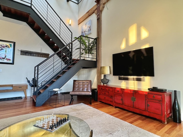 living area featuring light wood-style floors, stairway, and a high ceiling