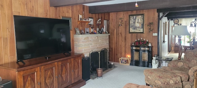 carpeted living area with beam ceiling, wooden walls, and a stone fireplace