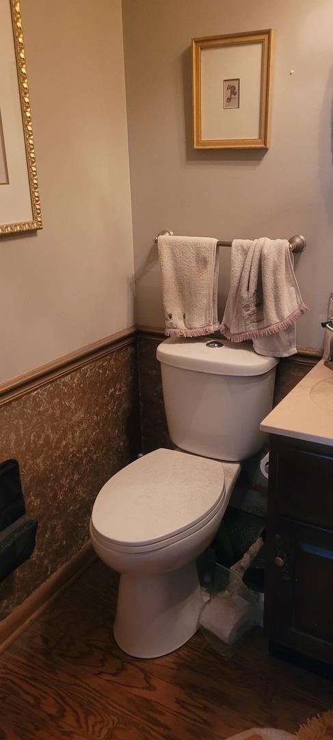 bathroom featuring a wainscoted wall, vanity, toilet, and wood finished floors