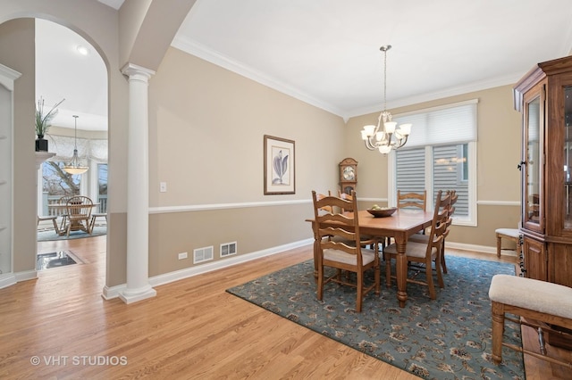 dining space featuring visible vents, crown molding, ornate columns, and wood finished floors