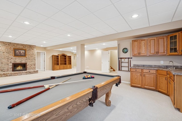 rec room featuring a drop ceiling, light colored carpet, a fireplace, a sink, and recessed lighting