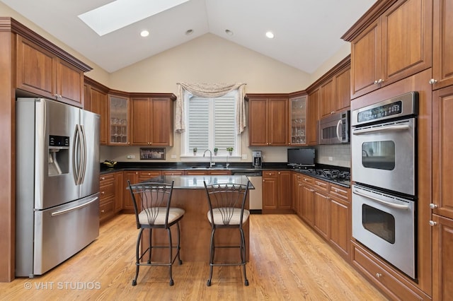 kitchen with dark countertops, brown cabinets, stainless steel appliances, and a kitchen breakfast bar