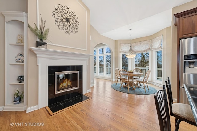 dining space featuring built in shelves, light wood-type flooring, a fireplace, and baseboards