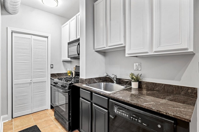 kitchen featuring light tile patterned floors, dark stone counters, white cabinets, black appliances, and a sink