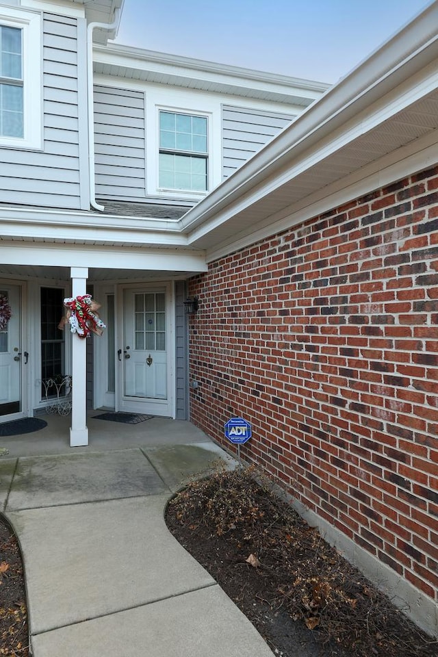 property entrance featuring brick siding and a porch