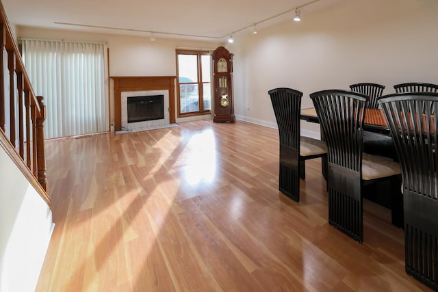 dining space with light wood-style floors, a fireplace, stairway, and baseboards