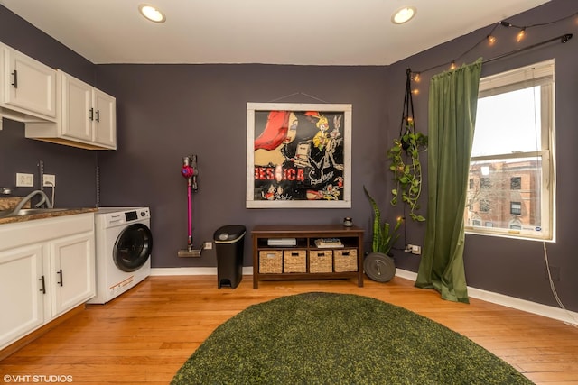 clothes washing area with light wood-type flooring, laundry area, baseboards, and washer / clothes dryer