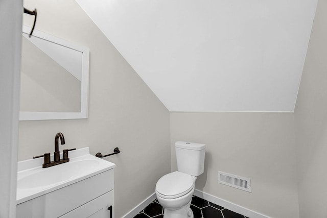 half bathroom with lofted ceiling, visible vents, toilet, vanity, and tile patterned flooring