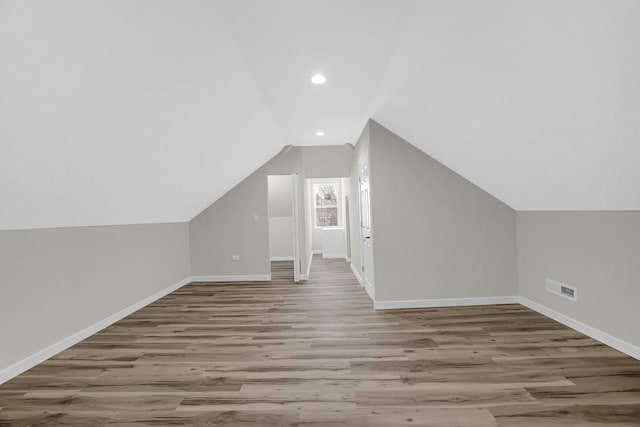 additional living space featuring recessed lighting, wood finished floors, visible vents, baseboards, and vaulted ceiling