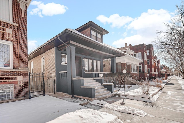 view of front facade featuring covered porch, brick siding, and a gate