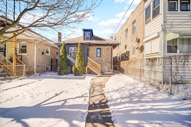 rear view of property featuring brick siding and fence