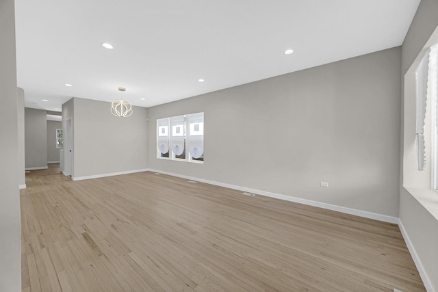 spare room with light wood finished floors, baseboards, a notable chandelier, and recessed lighting