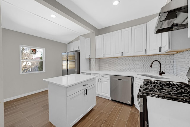 kitchen with lofted ceiling with beams, under cabinet range hood, a sink, appliances with stainless steel finishes, and wood tiled floor