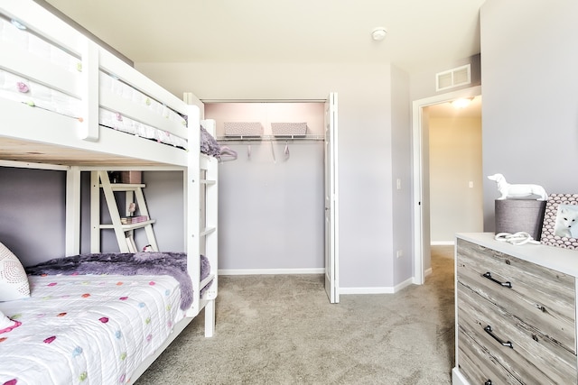 bedroom featuring a closet, visible vents, light carpet, and baseboards