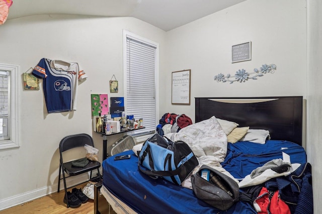 bedroom with baseboards, vaulted ceiling, and wood finished floors