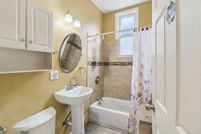 bathroom featuring shower / bath combination with curtain, toilet, and tile patterned floors