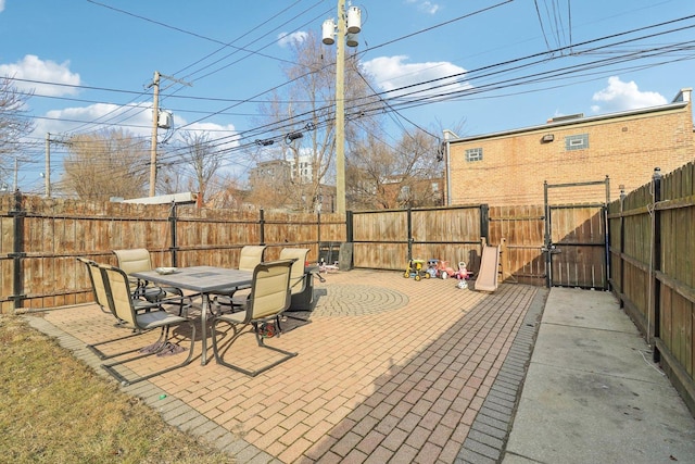 view of patio featuring outdoor dining space, a fenced backyard, and a gate