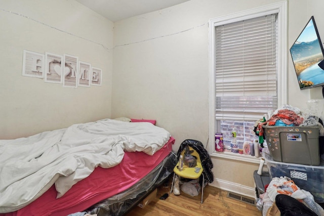 bedroom featuring wood finished floors, visible vents, and baseboards