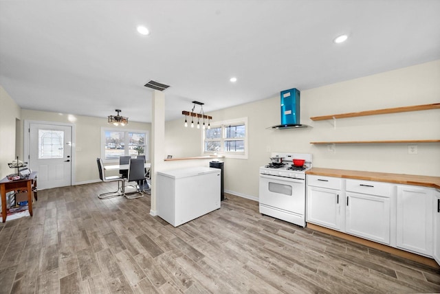 kitchen with butcher block countertops, refrigerator, range hood, light wood-type flooring, and gas range gas stove