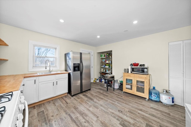 kitchen featuring appliances with stainless steel finishes, butcher block counters, a sink, and light wood-style flooring