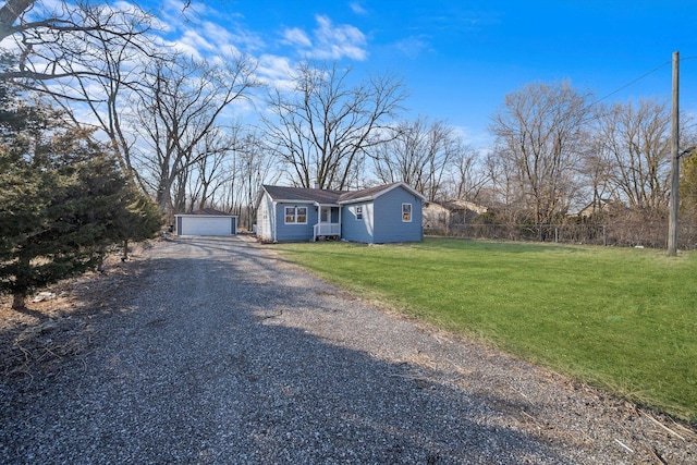 view of front of property featuring a front yard, an outdoor structure, a detached garage, and fence