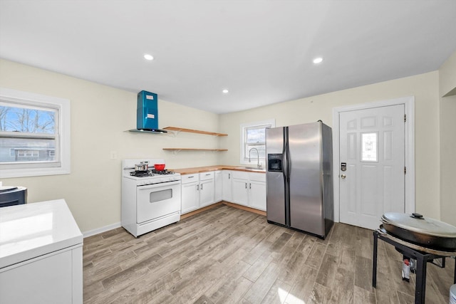 kitchen featuring range hood, light wood finished floors, stainless steel refrigerator with ice dispenser, and white gas range