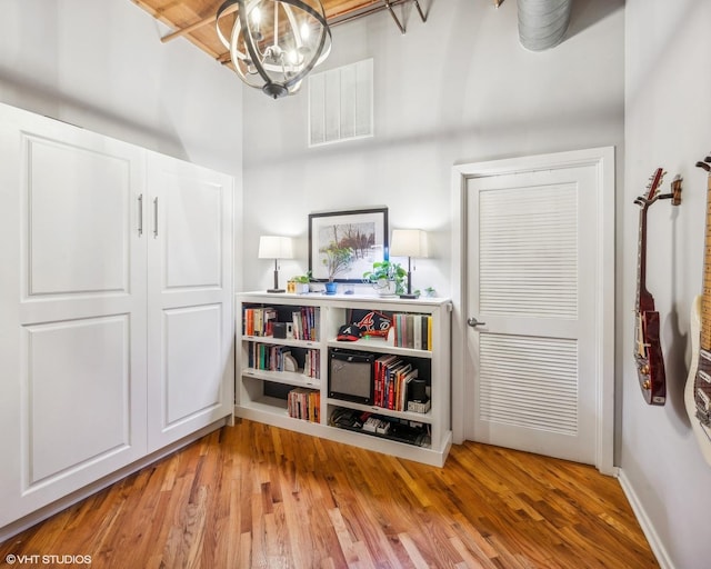 interior space with baseboards, light wood-style flooring, visible vents, and a notable chandelier