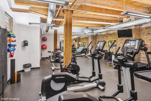 workout area with brick wall and baseboards