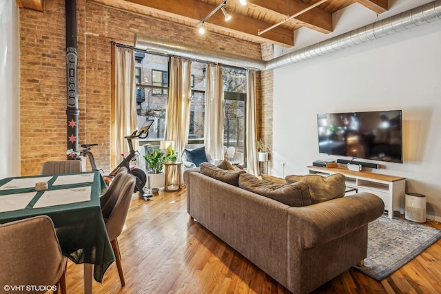 living room with brick wall, wood finished floors, and track lighting