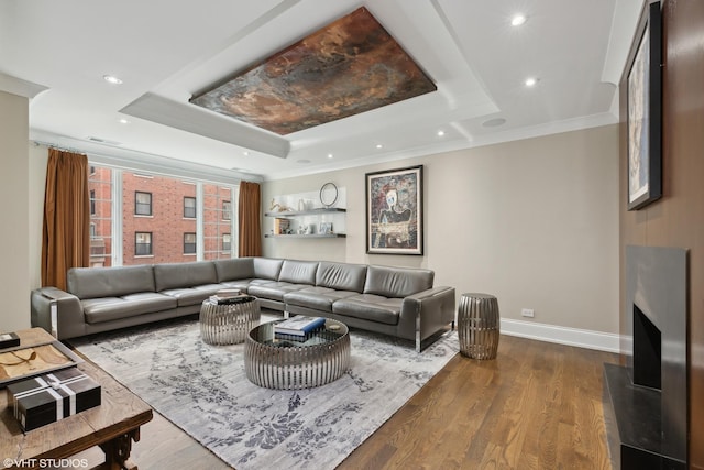 living area with baseboards, a raised ceiling, dark wood-style flooring, crown molding, and recessed lighting