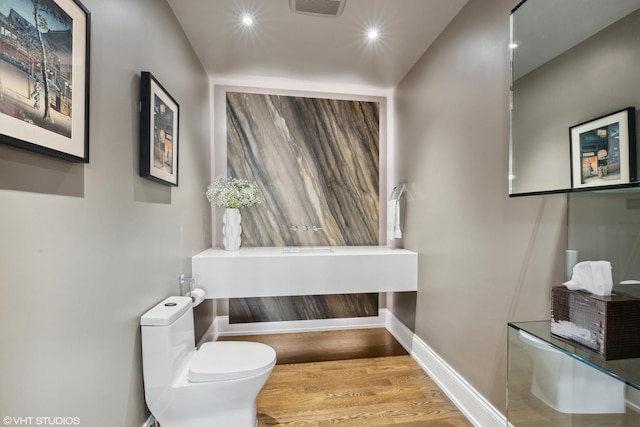 half bath featuring recessed lighting, wood finished floors, toilet, and baseboards