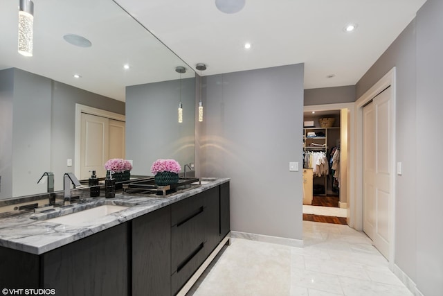 full bath with vanity, baseboards, a walk in closet, and recessed lighting