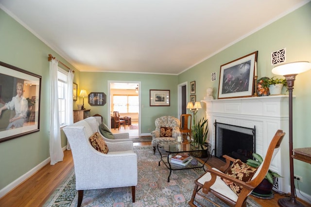 living room featuring ornamental molding, a brick fireplace, baseboards, and wood finished floors