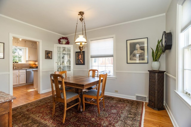 dining space with visible vents, crown molding, light wood-type flooring, and baseboards