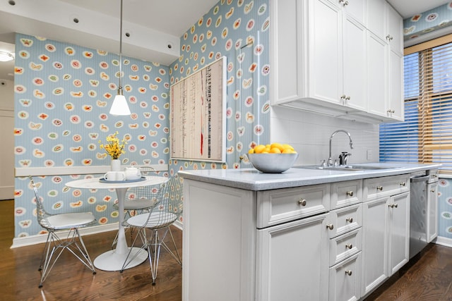 kitchen featuring wallpapered walls, white cabinetry, light countertops, and decorative light fixtures