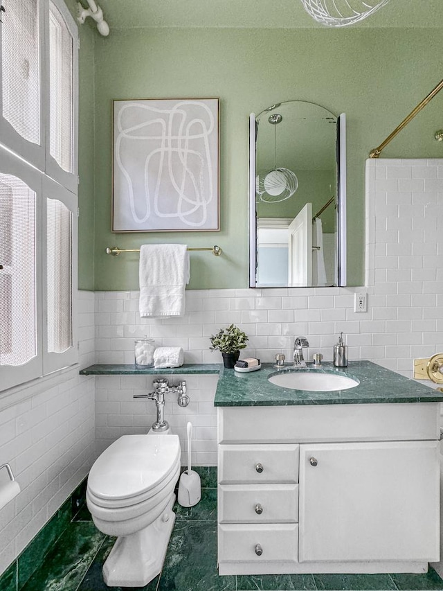 full bath featuring tile patterned floors, vanity, toilet, and tile walls