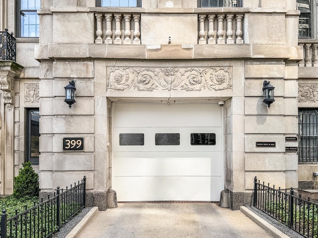 garage with concrete driveway and fence