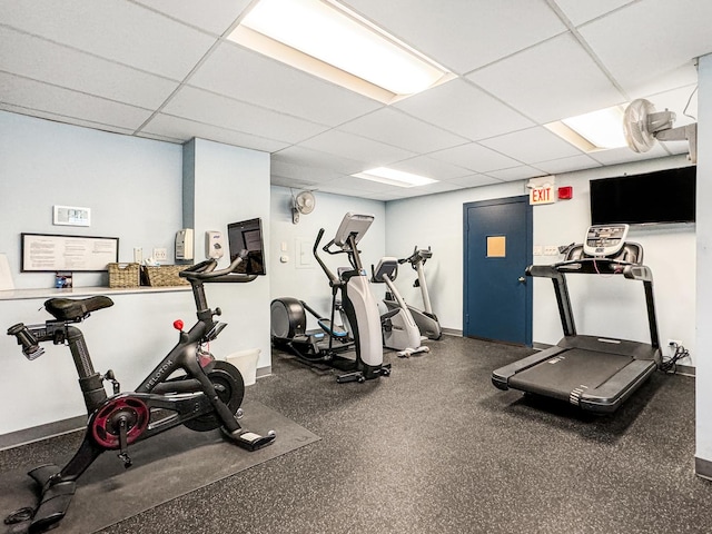 gym with a paneled ceiling and baseboards